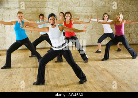 Eine Gruppe von Frauen, die das Training mit Fitness-Trainer in der Turnhalle Fokus auf die Frau im roten Hemd Seitenansicht Stockfoto