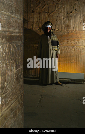 Guide posiert für die Kamera in ein goldenes Leuchten in den Kammern innerhalb der inneren Tempel des Horus Tempel, Edfu, Ägypten Stockfoto