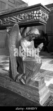 Detail einer kunstvoll geschnitzten hölzernen Engel Figur kniend und betend in einem kleinen Dorf Kirchenraum hautnah Stockfoto