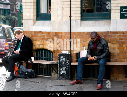 London Reportageaufnahme von zwei Menschen, die eine Pause, eine schwarze, eine weiße Stockfoto