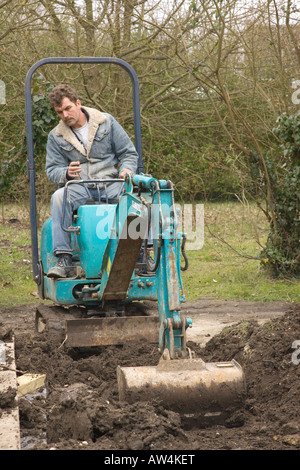 ein Mann fährt ein Minibagger / Bagger Stockfoto