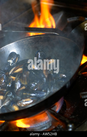 Kochen der Muscheln in Weißwein mit Flammen im Hintergrund Stockfoto