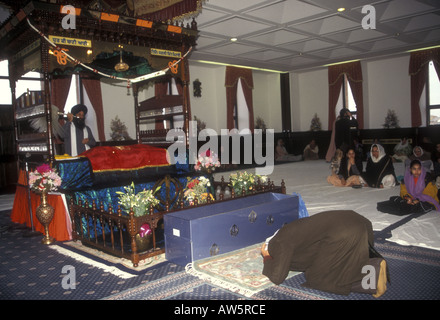 Eine Sikh-Frau kniet in Respekt vor dem Guru Granth Sahib, dem heiligen Sikh-Buch oder lebenden Guru, auf einem palki oder Altar in der Gurdwara. Stockfoto