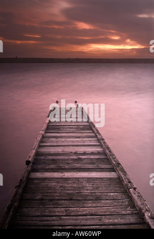 Steg bei Sonnenuntergang an der Flotte Lagune hinter Chesil Beach Weymouth, Dorset Stockfoto