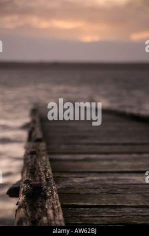 Steg bei Sonnenuntergang an der Flotte Lagune hinter Chesil Beach Weymouth, Dorset Stockfoto