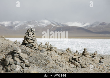 Steinerne Cairns Stand im Vordergrund auf den gefrorenen Ufern des See Namtso, was bedeutet "Himmlischen See", in Tibet Stockfoto