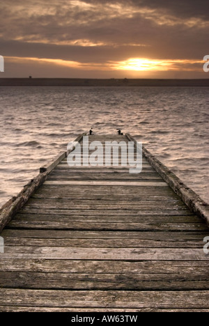 Steg bei Sonnenuntergang an der Flotte Lagune hinter Chesil Beach Weymouth, Dorset Stockfoto