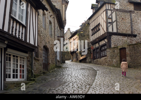 Ein junges Mädchen geht auf dem Kopfsteinpflaster vorbei an hölzernen Fachwerkhäusern auf mittelalterlichen Rue de Jerzual in Dinan, Bretagne Stockfoto