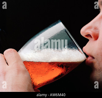 MANN TRINKT BIER/ALE MIT SCHAUMIGEN KOPF Stockfoto