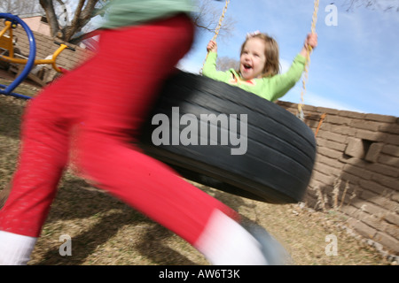 Kinder spielen im Freien auf Reifen schwingen, Lächeln Stockfoto