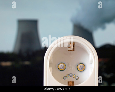 Steckdose mit einem traurigen Gesicht gemacht aus Euro-Münzen-Kraftwerk bei dampfendem Kühlturm im Hintergrund Stockfoto