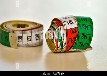 Zwei Maßband (cm) der Näherin gerollt, ruht auf einem weißen Tisch. Stockfoto
