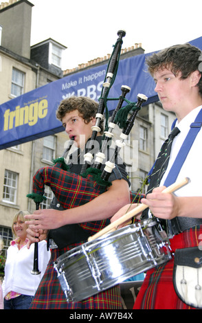 Zwei junge Männer in schottischen nationalen Kleid spielt Dudelsack und Trommel infront von Edinburgh Fringe Festival-banner Stockfoto