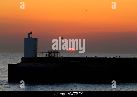 Untergehenden Sonne fällt hinter Leuchtturm am Pier Brighton Marina uk Stockfoto