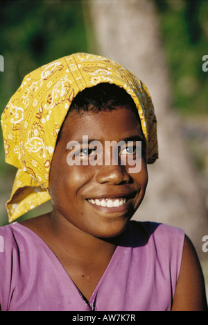 Ein 12 Jahre altes Mädchen in Fidschi lächelt breit, wie sie ein neues Halstuch trägt. Stockfoto