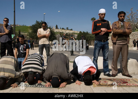 Palästinenser beten als Israelische Polizisten bewachen in Ost Jerusalem, Israel Stockfoto