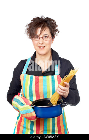 Hausfrau in Schürze, ein Spaghetti ungekocht in der blauen Pfanne einführt Stockfoto