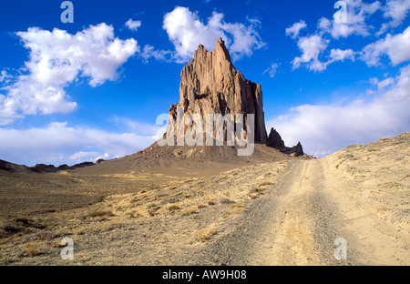 Nachmittags Licht auf Shiprock und Feldweg unter blauem Himmel und Wolken Navajo Indianerreservat New Mexico USA Stockfoto