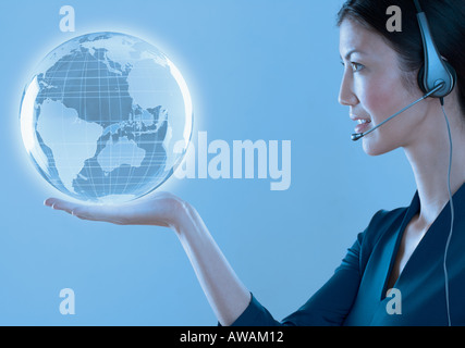 Frau mit Kopfhörer hält einen Globus Stockfoto