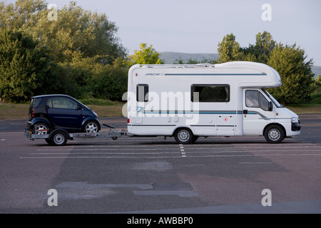 Wohnmobil schleppen einen schicken Wagen auf einem Anhänger, in eine M5-Autobahnraststätte geparkt. Stockfoto