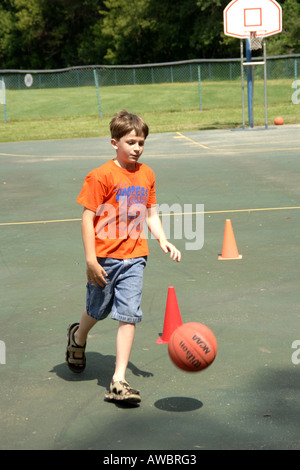 Junge Männchen spielen Basketball unter Aufsicht im Summercamp in Michigan Stockfoto