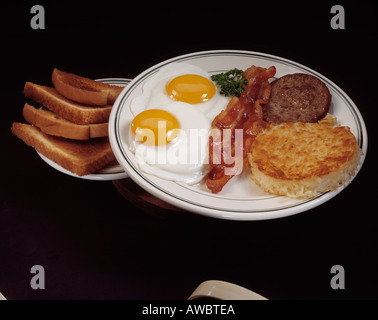 herzhaftes Frühstück Teller zwei Spiegeleier Sonnenseite Speck Streifen Wurst Fleisch Patty Rösti Home Braten Kartoffel Kartoffeln toast Stockfoto