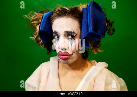 junge Frau im gotischen Puppe/Clown Make-up mit blauen Schleifen im Haar sieht traurig Stockfoto