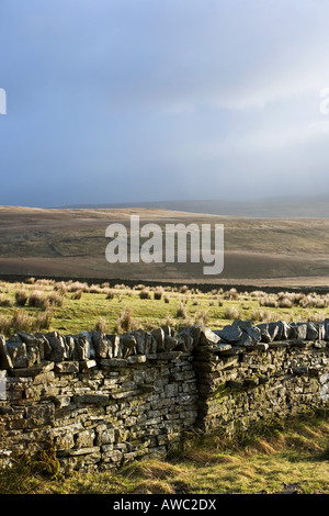 Dunkle Regenwolken über einen trockenen Stein Wand angrenzende Winton fiel, Cumbria, UK Stockfoto