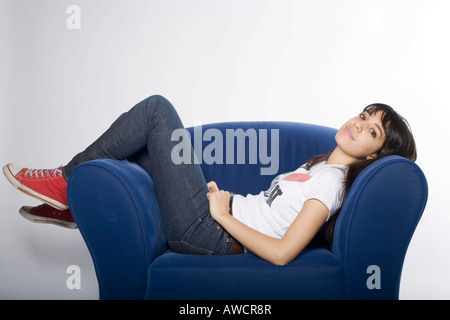 Junge Frau auf einem blauen Sessel bequem liegend Stockfoto