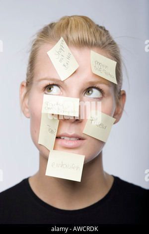 Junge Frau mit vielen Post-It Zettel ins Gesicht Stockfoto