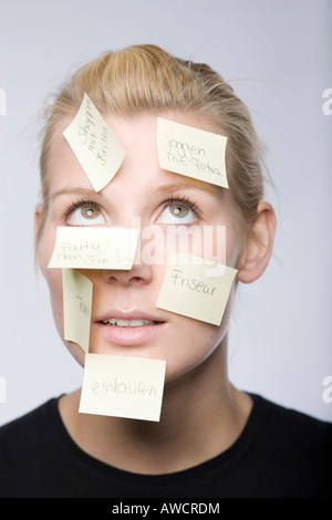 Junge Frau mit vielen Post-It Zettel ins Gesicht Stockfoto