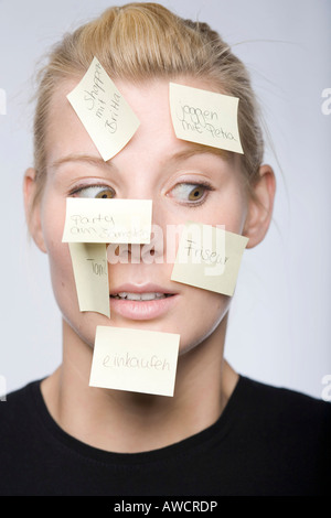 Junge Frau mit vielen Post-It Zettel ins Gesicht Stockfoto