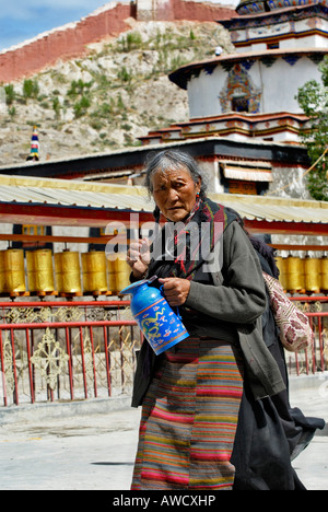 Pilger mit Teekanne vor Gebetsmühlen, Paelkhor Choede Kloster, Gyantse, Tibet Stockfoto