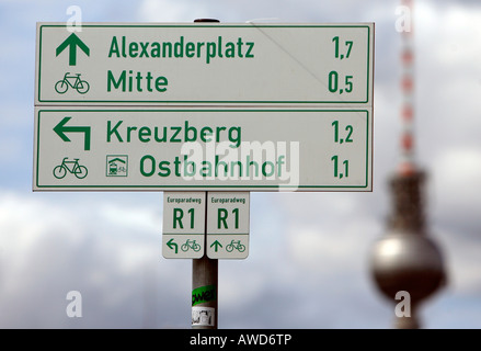 Radtour im Himmel - Zeichen neben alten Straßenlaternen und den Fernsehturm zeigen Wegbeschreibungen zu verschiedenen Orten in Berlin, Deutschland Stockfoto