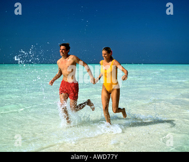 Junges Paar joggen durch flaches Wasser, Malediven, Indischer Ozean Stockfoto