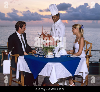 Junges Paar bei Sonnenuntergang genießen Sie eine Abendessen mit Hummer, Luxus Urlaub, Malediven, Indischer Ozean Stockfoto