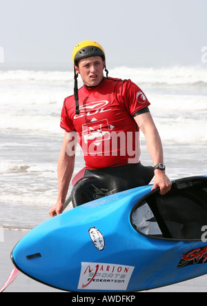 Mann trägt seine Surf-Kajak am Strand vom Meer entfernt Stockfoto