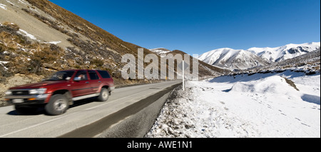 Ein rote SUV beschleunigt entlang State Highway 73 an Porters Pass New Zealand Südalpen Stockfoto