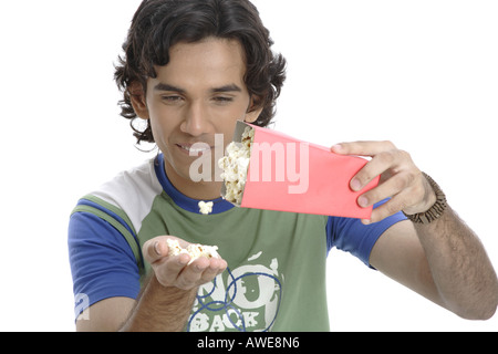 ANG200445 Teenager Packung Popcorn in einer holding und gießt es auf der anderen Seite lächelt Herr 687T Stockfoto