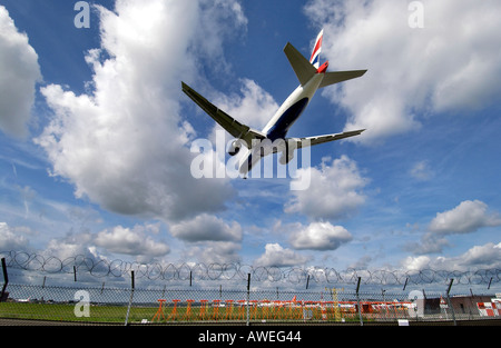 Ein British Airways-Jet landet am Flughafen Gatwick über den Stacheldraht-Umzäunung Stockfoto