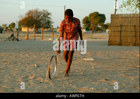 Jungen spielen mit Felge auf der Straße, Sehitwa, Botswana, Afrika Stockfoto