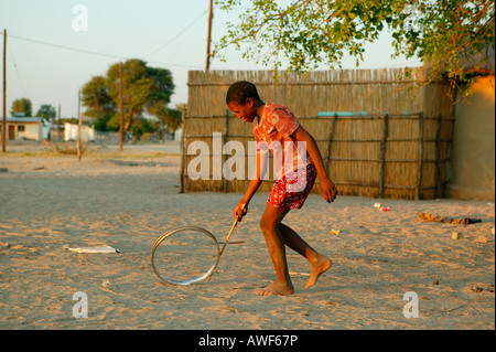 Jungen spielen mit Felge auf der Straße, Sehitwa, Botswana, Afrika Stockfoto