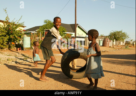 Junge spielt auf unbefestigten Straße mit alten Reifen, Sehitwa, Botswana, Afrika Stockfoto