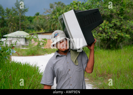 Mann trägt Fernseher zu seinem Haus, einheimischen Arawak, Santa Mission, Guyana, Südamerika Stockfoto