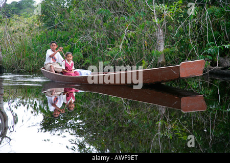 Junge hob seine jüngere Schwester von der Schule mit seinem Boot, Eingeborenen Arawak, Santa Mission, Guyana, Südamerika Stockfoto