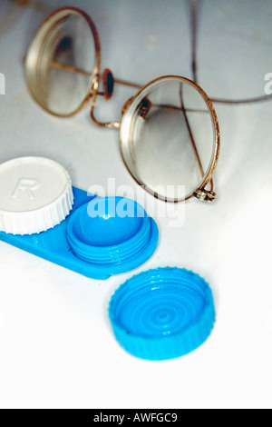 Stillleben mit ein paar getönten Metall gerahmten Golddraht umrandeten Brille und eine blaue Kontaktlinsenbehälter auf einem Waschbecken-Zähler Stockfoto