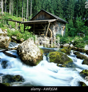 Wassermühle Rad neben einem kleinen Wasserfall in einem Bergbach mit Moos bewachsenen Felsen Stockfoto