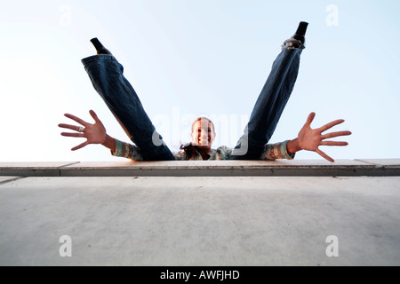 Verrücktes Mädchen an einer Wand, Strecken ihre Arme und Beine Stockfoto