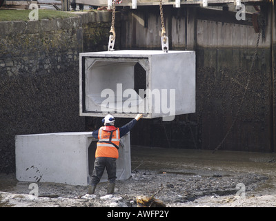 Workman Regie 5 Tonnen Betonblöcken in Bude Kanal, die eingehende Flut so Meer Schleuse entfernt werden können Stockfoto