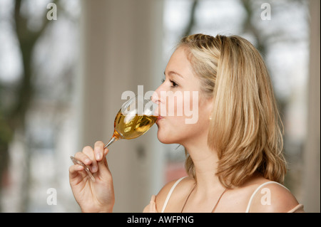 Junge blonde Frau trinkt ein Glas Weißwein Stockfoto